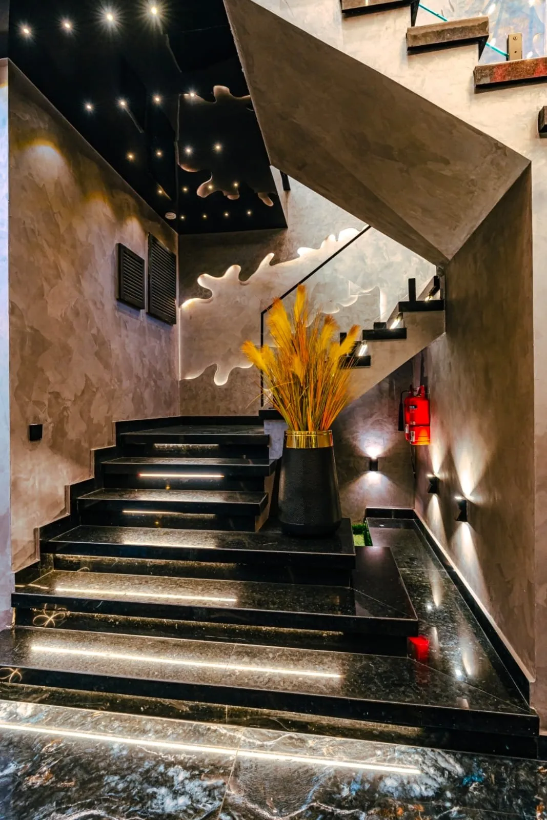 Staircase with dark steps and a glass railing.