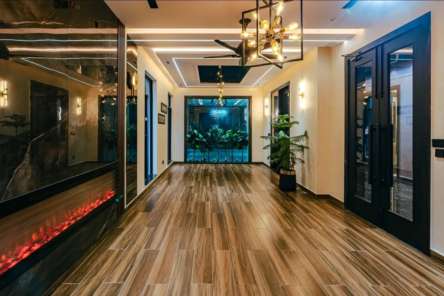Living area with wood-look flooring, pendant lights, and a wall-mounted fireplace.